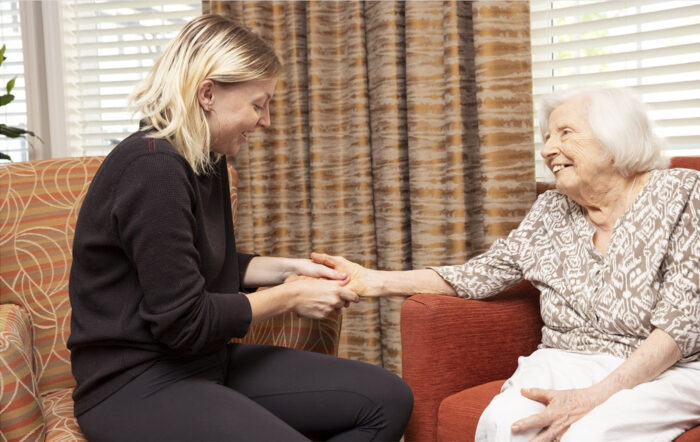 blonde caregiver helping senior woman