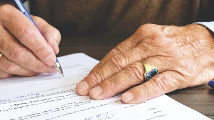 senior signing his name on a document