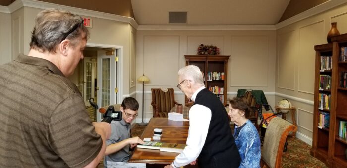 Independence Village residents looking at books with a student