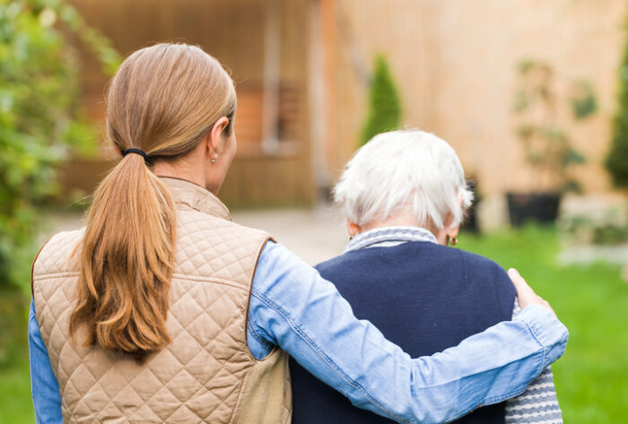 caregiver walking with elderly woman in the park