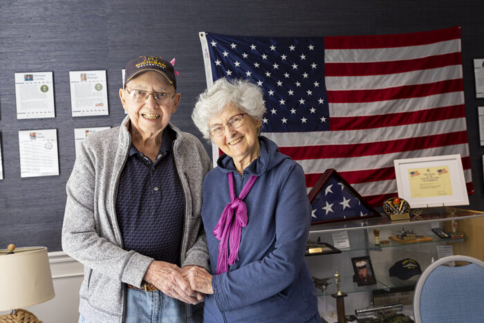 an elderly couple standing in front of a flag