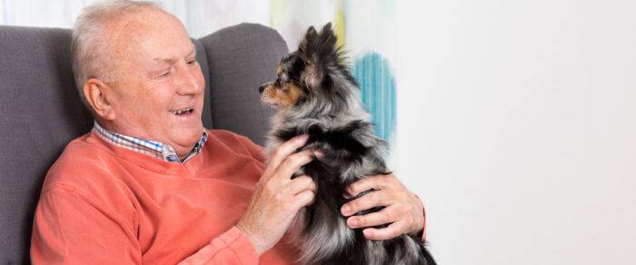 senior sitting while holding his dog