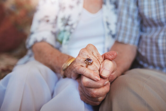 senior couple holding hands while sitting together