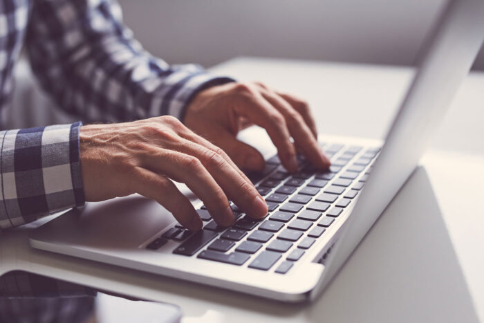 man typing on a laptop