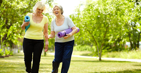 two women walking outside with yoga mats