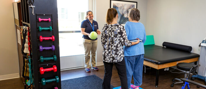 independence village fitness instructor members helping a resident exercise with arthritis