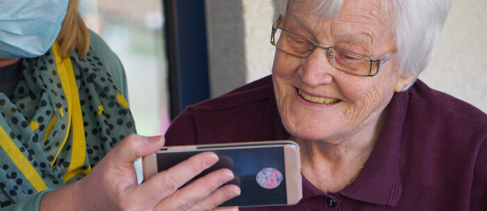 elderly women watching a video and smiling on a smart phone