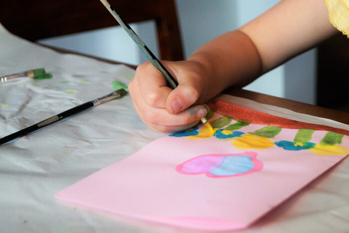 grandchildren painting their grandparents a card for their care package