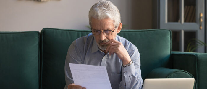 Elderly man reading over some common senior scams
