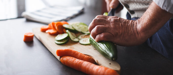 senior chopping up fresh vegetables in the kitchen