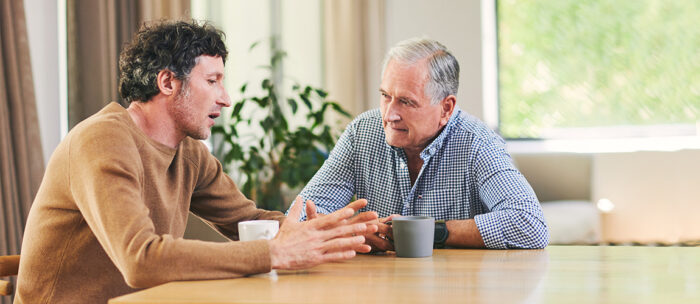 Father and adult son discussing dementia at the dinner table over coffee