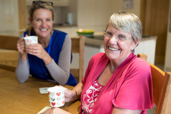 senior living caregiver and resident having coffee