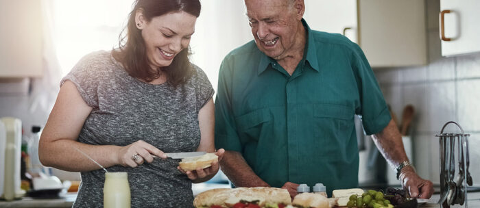 senior and his daughter cooking together in the kitchen while laughing