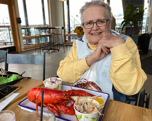 Resident Audrey smiling with lobster during a StoryPoint trip to maine