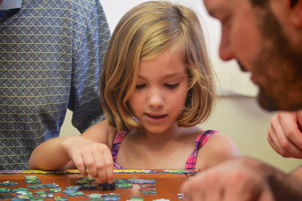 girl doing a puzzle with family