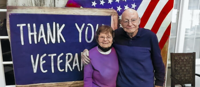 seniors stand in front of a veterans day banner