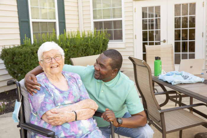 Senior woman and caregiver on patio smiling