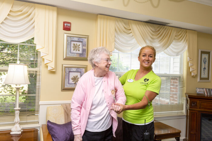 Caregiver in green helping elderly woman