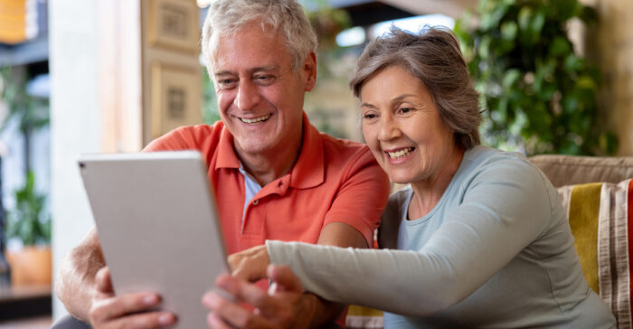 Happy senior couple looking at social media on a tablet computer