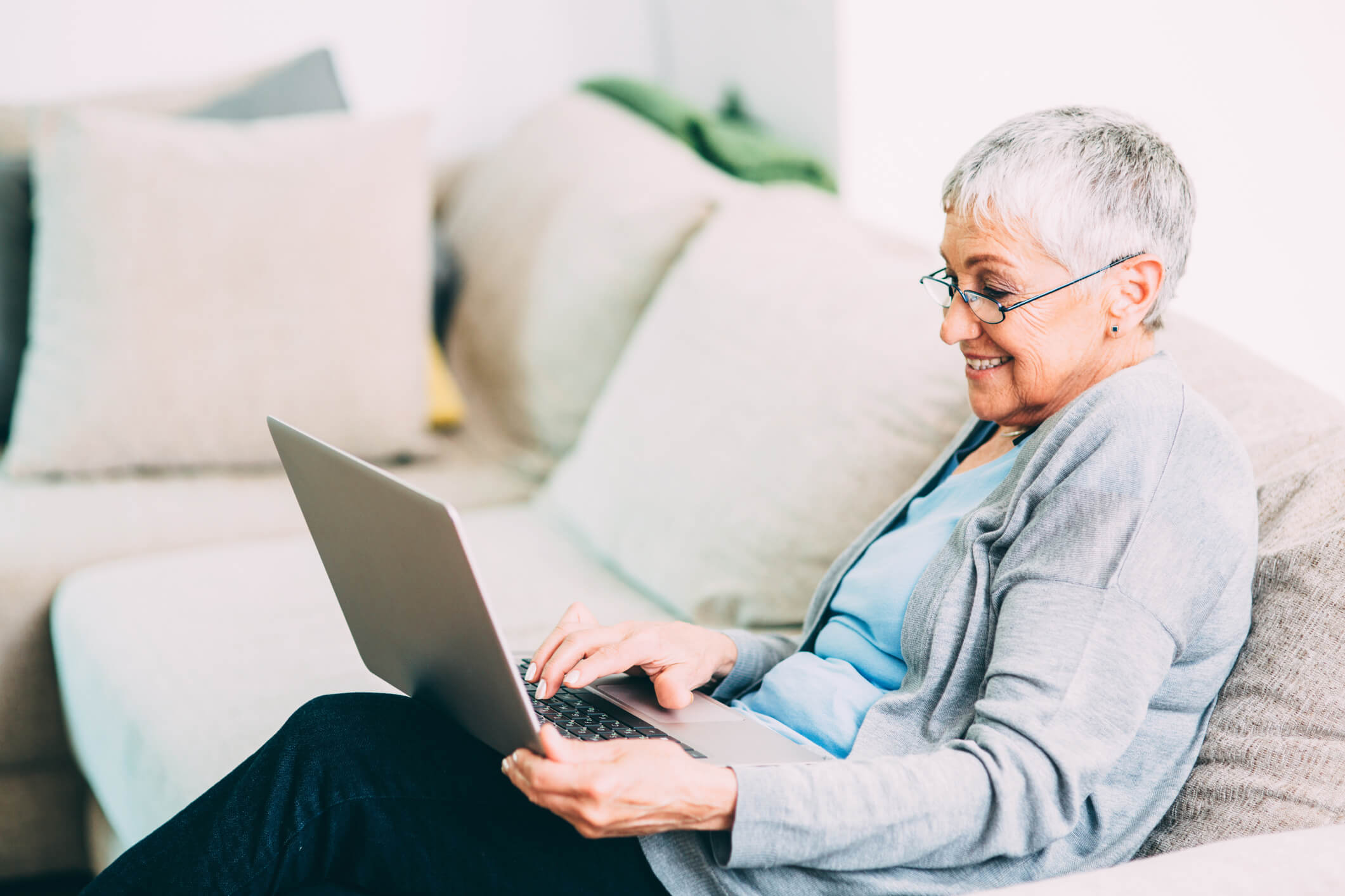 senior living resident using a laptop on the couch