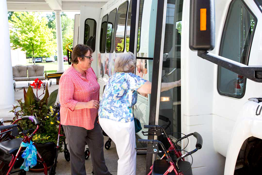 StoryPoint senior living resident getting onto bus with help from employee