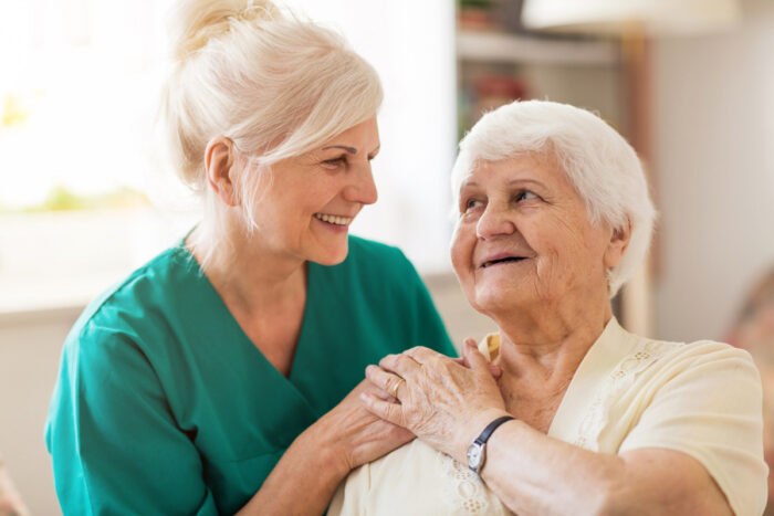 caregiver and senior woman smiling at each other