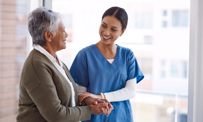 caregiver holding hand of resident while walking