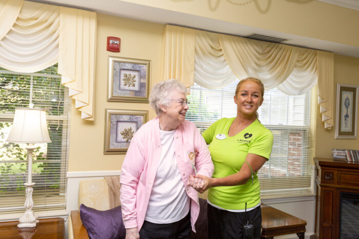caregiver holding hand of senior woman in living room