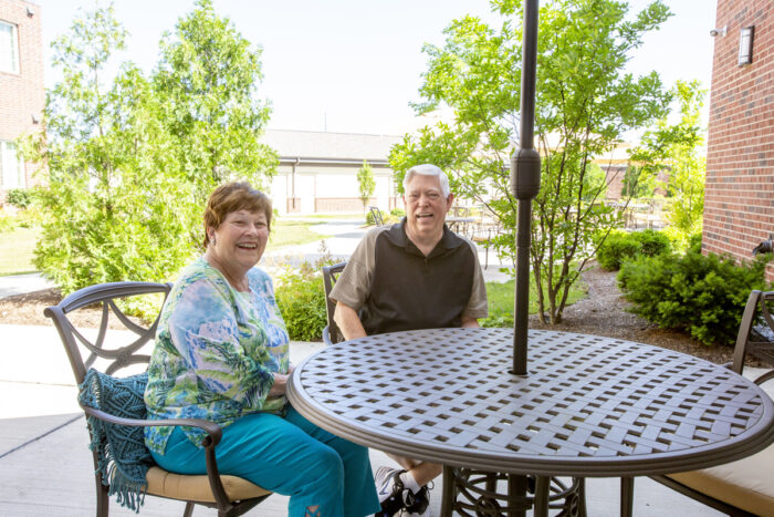 couple of senior sitting outside smiling