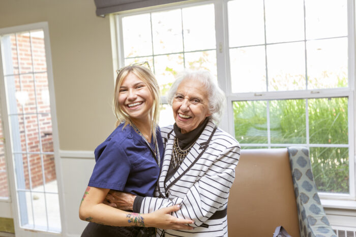 senior woman and caregiver hugging and smiling