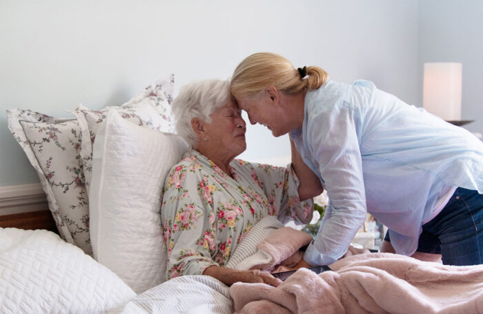 senior woman hugging daughter in hospital bed