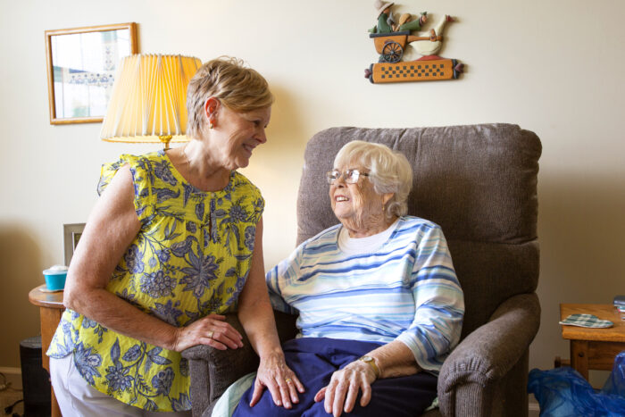 senior woman sitting in sofa smiling to caregiver