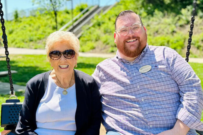 resident and caregiver sitting on a swing smiling