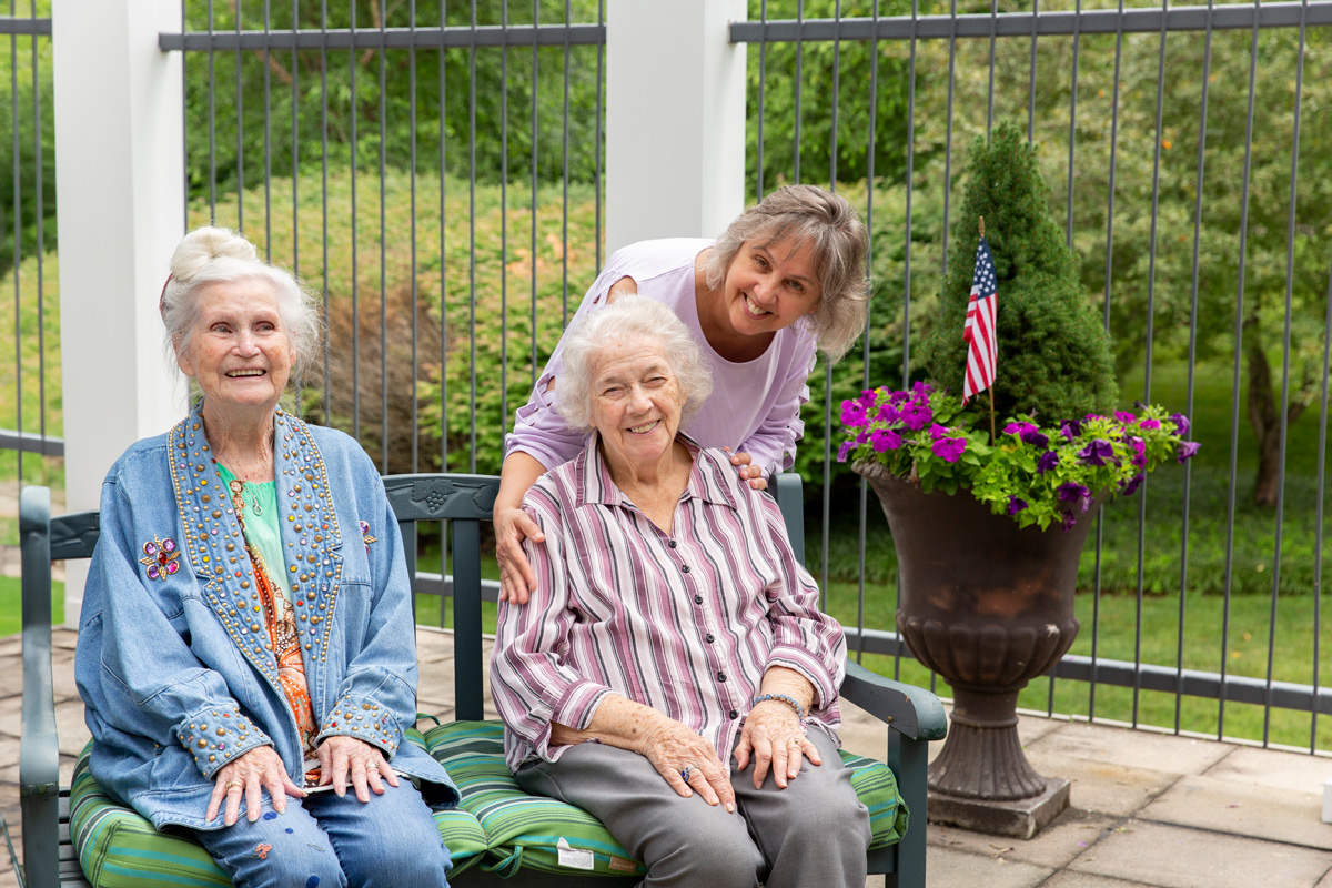 two StoryPoint memory care residents sitting outside with employee