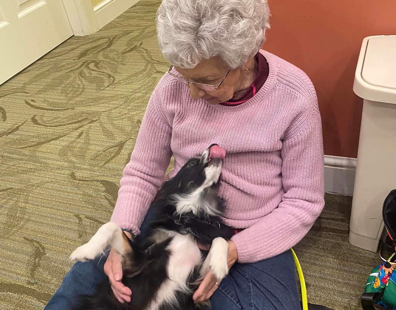 Danbury Senior Living Resident petting dog in her lap