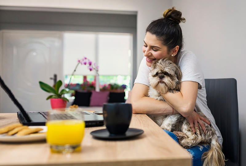 woman hugging dog at her laptop